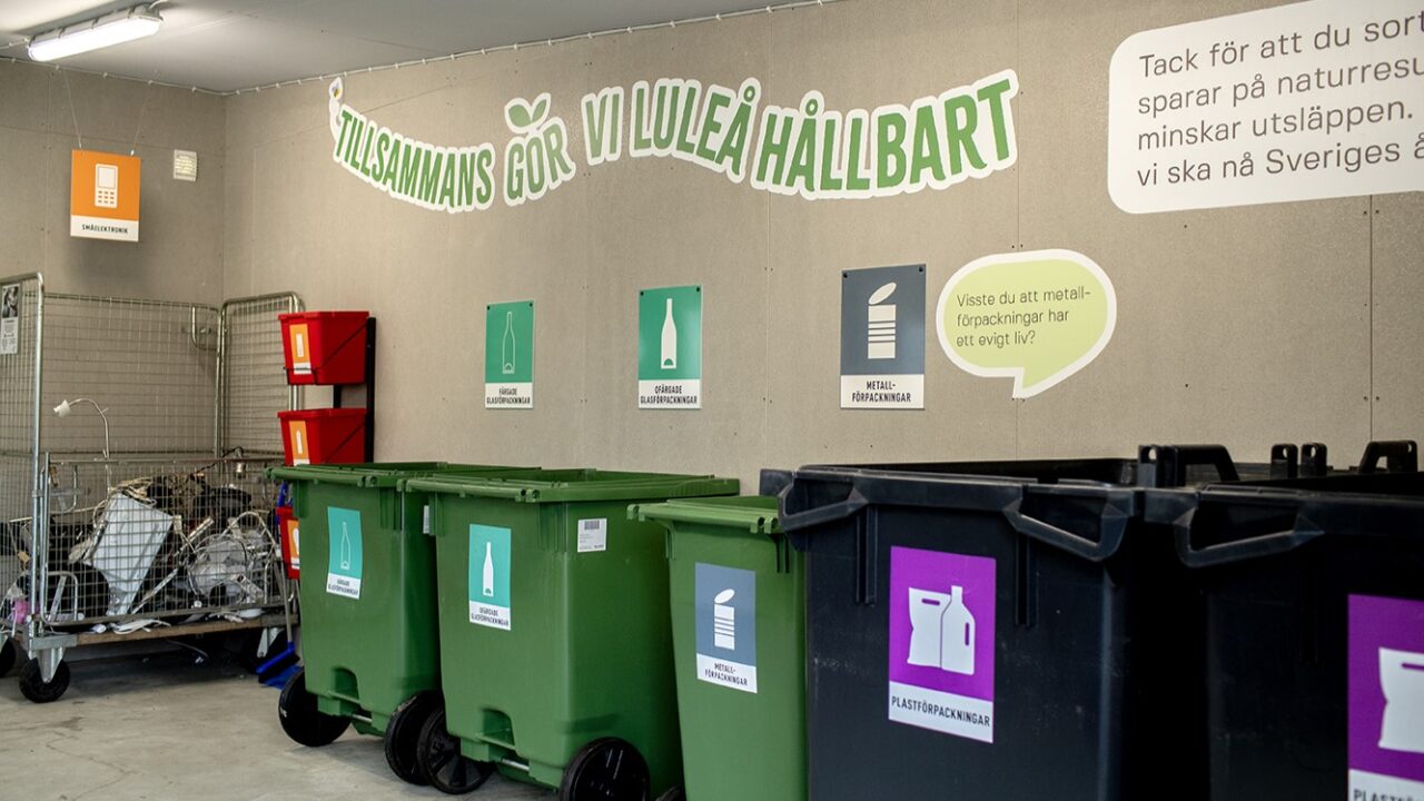 Bild på ett miljörum för insamling av avfall med färgglada kär och skyltar som beskriver hur det ska ske