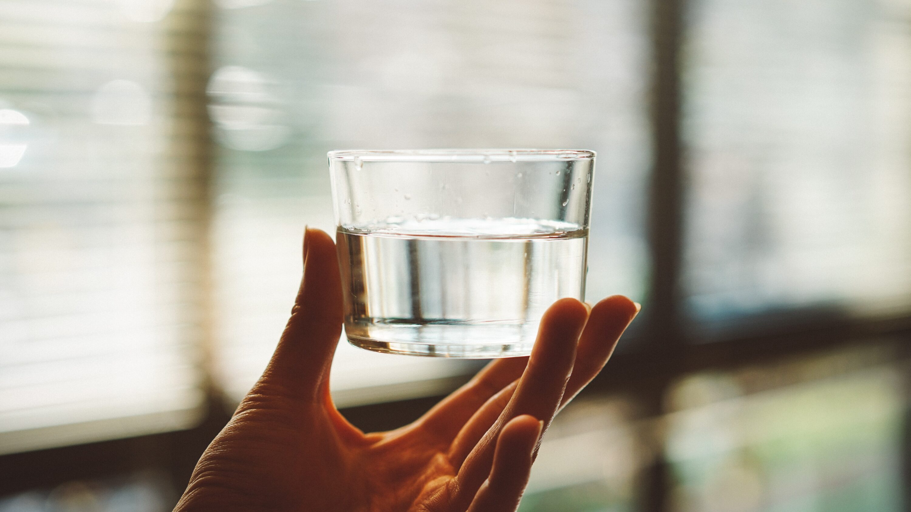 Bild på en hand som håller i ett glas med vatten