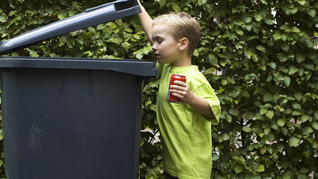Bild på en pojke som öppnar ett avfallskärl